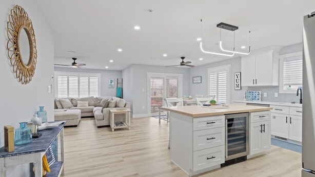 Une cuisine moderne avec des meubles blancs, un îlot central et un coin repas comprenant une table et des chaises blanches.