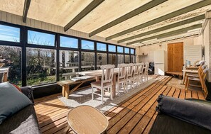 A wooden deck with a dining area, large windows, and a kitchen area. - Awesome home in Allinge with WiFi (Allinge)