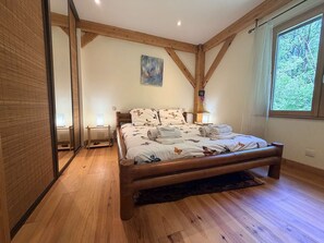 A bedroom with a wooden bed, a large window, and a painting on the wall. - La maison du Dolmen 4 or 6 p with private swimming pool (LE BUISSON DE CADOUIN)