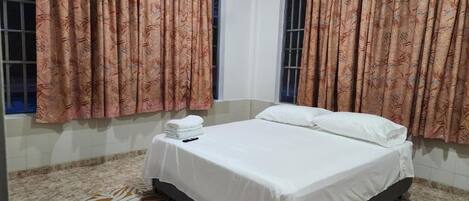 Un dormitorio con cama, cortinas y ventana.