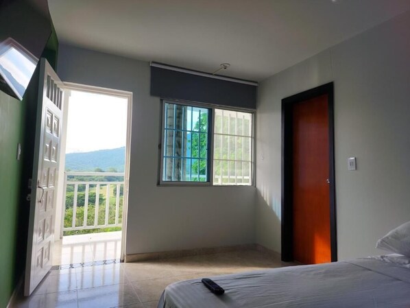 A bedroom with a bed, a window, and a door. - Hotel OK el eden (Tocaima)