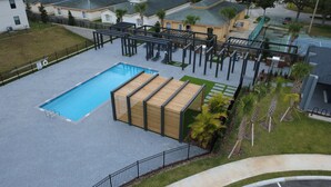 Oversigtsbillede af et poolområde med træterrasse, overdækket opholdsområde og indhegnet pool.