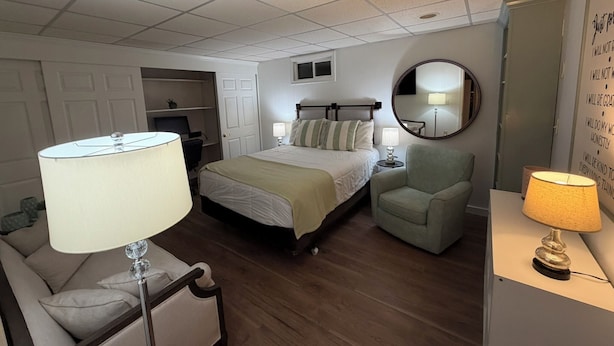 Ein Hotelzimmer mit einem Bett, einem Sessel, einem Schreibtisch, einer Lampe, einem Spiegel und einer Wand mit motivierenden Zitaten.