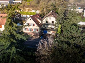 A two-story house with a sloped roof, surrounded by dense trees and a small driveway. - Darjeeling Guest Room (Boersch)