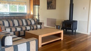 Una sala de estar con sofá, mesa de centro, chimenea y piso de madera.