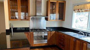 Una cocina con armarios de madera, una campana extractora de acero inoxidable, un horno empotrado y un lavavajillas.
