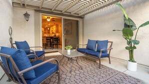 Un espace patio aménagé avec une table, deux chaises bleues dotées de coussins et une plante en pot.