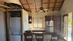Una cocina compacta con horno integrado, refrigerador y una barra con taburetes.