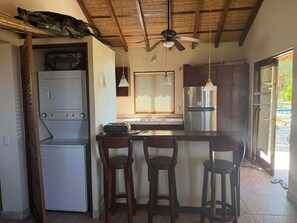 A compact kitchen with a built-in oven, a refrigerator, and a bar area with stools.