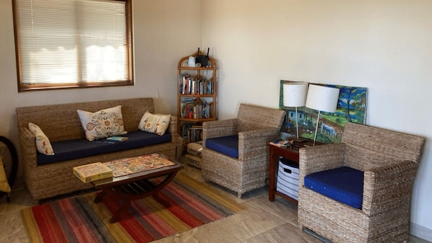Una sala de estar acogedora con un sofá, dos sillones, una mesa de centro, una estantería y un cuadro en la pared.