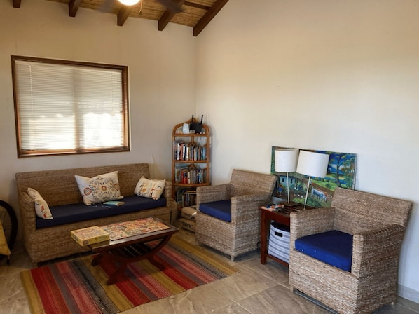 A cozy living room with a sofa, two armchairs, a coffee table, a bookshelf, and a painting on the wall.