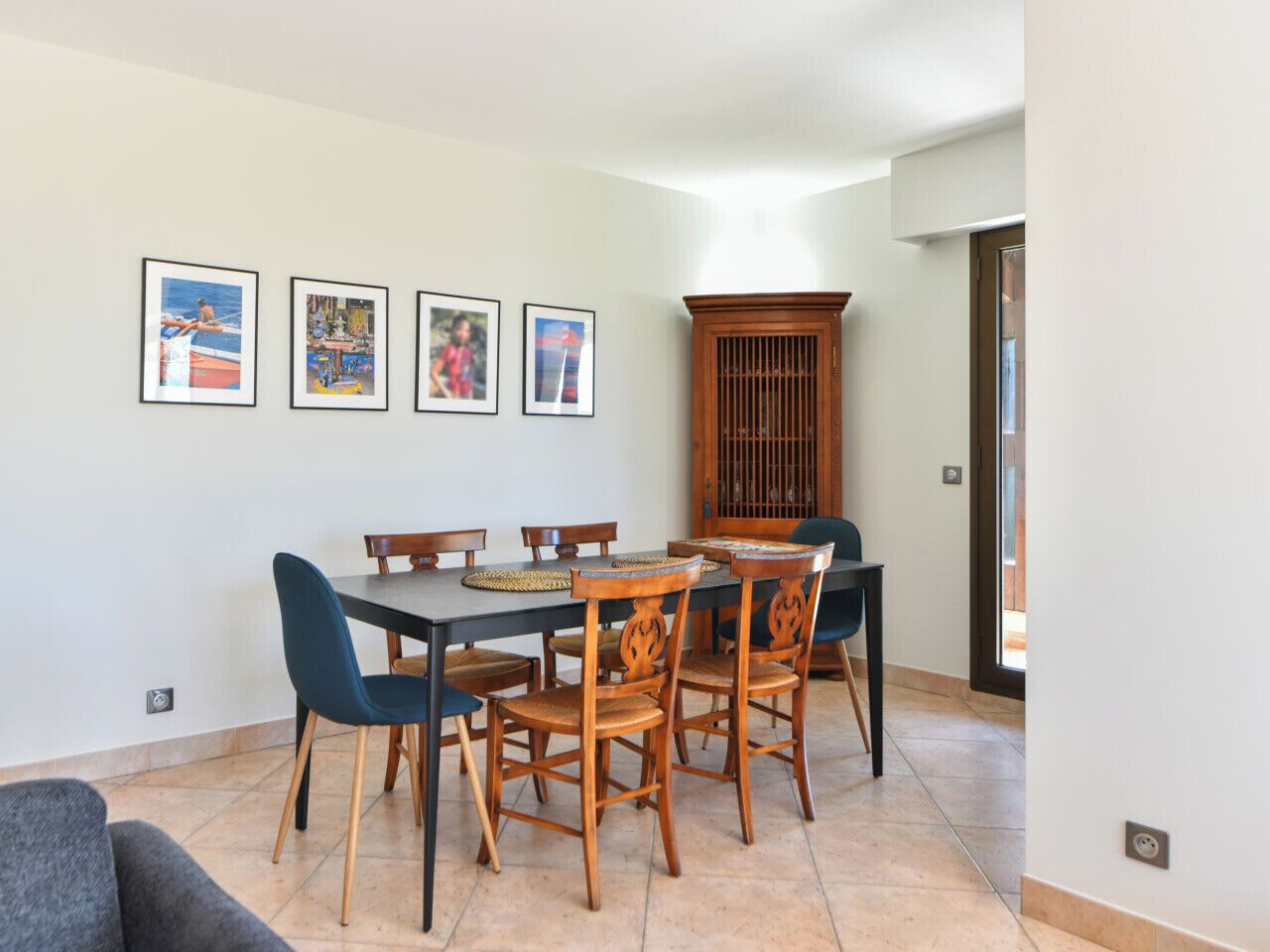 A dining area with a rectangular table, six chairs, and four framed pictures on the wall.