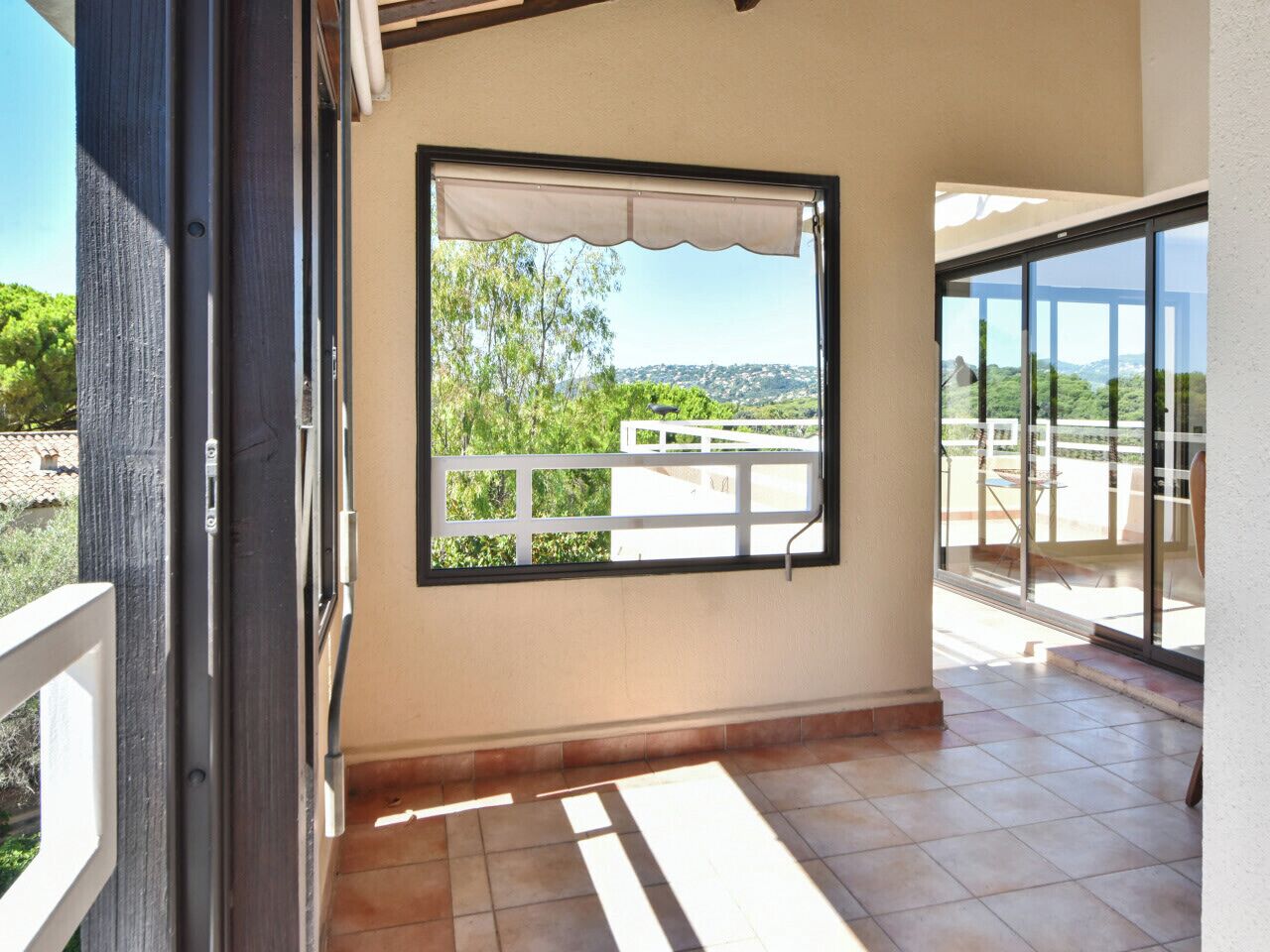 A balcony with a view of greenery and a distant landscape.