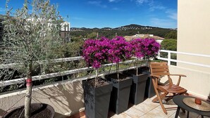 En terrasse med udsigt over landskabet, en træstol og plantekasser.