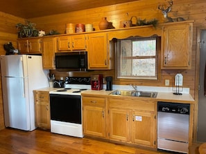 A kitchen with wooden cabinets, a refrigerator, stove, microwave, sink, and dishwasher. - Blushing Bear Stunning Views (Sevierville)