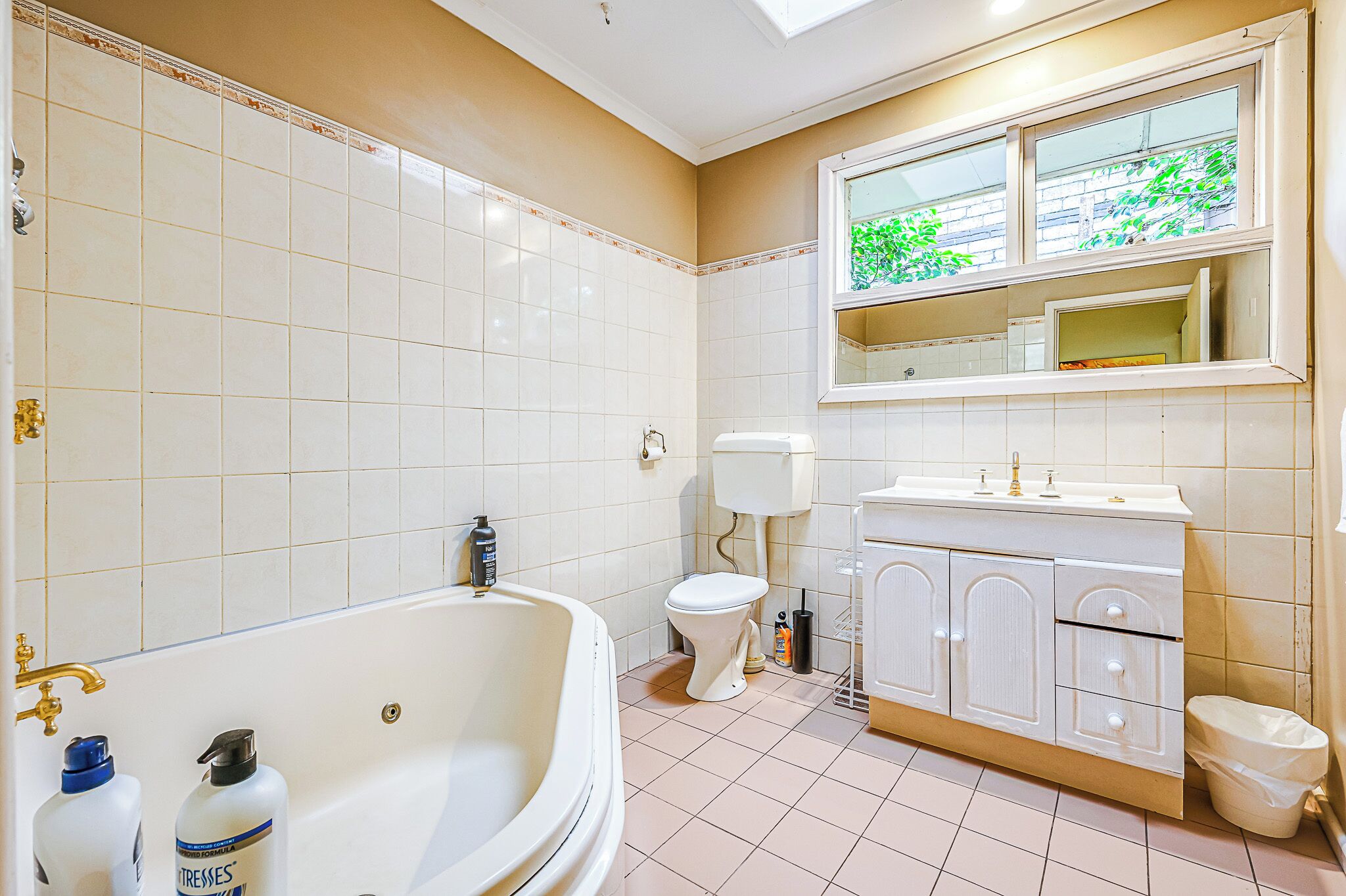 Ein Badezimmer mit Badewanne, Toilette und Waschtisch mit Spiegel.