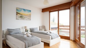 Une chambre avec deux lits, un tableau et un balcon avec vue.