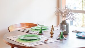 A dining table with green plates, a glass, and a vase with branches. - Roma Norte - Sunny and Mid-Century Modern Casa Apache (Ciudad de México)