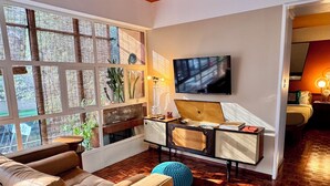 A modern living room with a large window, a flat-screen TV, a wooden coffee table, and a comfortable sofa. - Roma Norte - Sunny and Mid-Century Modern Casa Apache (Ciudad de México)