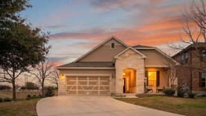 Una moderna casa a due piani con facciata in pietra, un ampio garage e un prato curato.