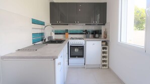 A compact kitchen with dark cabinets, a white stove, and a sink. - Bénodet - 150 m from the beach, restaurants and thalasso centre (BENODET)
