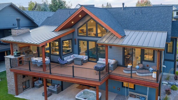 Ein zweistöckiges Haus mit überdachter Terrasse, Sitzgelegenheiten im Freien und einem Whirlpool.