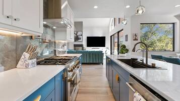 A modern kitchen with a central island, built-in oven, and a large window.
