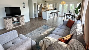 A modern living room with a large gray sectional sofa, a flat-screen TV, and a ceiling fan.
