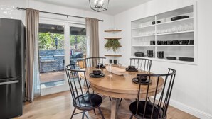 A modern kitchen with a round wooden table, black chairs, and a built-in shelf with glassware. - Retreat home tucked away in the forest, perfect for big groups, near Bass Lake (Oakhurst)