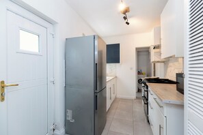 Eine kleine Küche mit Kühlschrank, Herd, Mikrowelle und weißen Schränken.