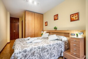 Un dormitorio con cama, armario de madera, mesita de noche y una obra de arte colgada en la pared.