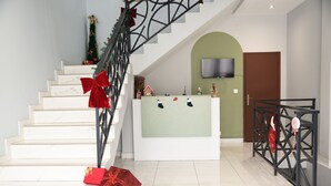 A staircase with red bows, a reception desk, and a TV mounted on the wall. - Résidence Soavina (Antananarivo)