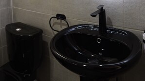 A bathroom with a black sink, a mirror, and a framed picture on the wall. - Résidence Soavina (Antananarivo)