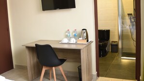 A hotel room with a bed, a desk with a chair, a television, a shower area, and a toilet. - Résidence Soavina (Antananarivo)