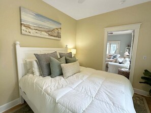 Ein Schlafzimmer mit einem Bett, Kissen, einem Bild an der Wand und einer Tür zu einem anderen Raum.
