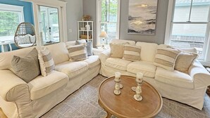 Ein Wohnzimmer mit einer Eckcouch, einem runden Couchtisch und einem Gemälde an der Wand.