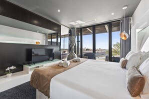 Une chambre d’hôtel moderne dotée d’un grand lit, d’une télévision à écran plat, d’un vase et offrant une vue sur la ville.
