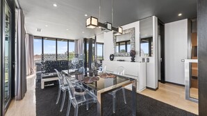 A modern kitchen with a glass table, clear chairs, and a pendant light. - Penthouse Grand Noir | Outdoor Jacuzzi | Near the Strip (Albufeira)