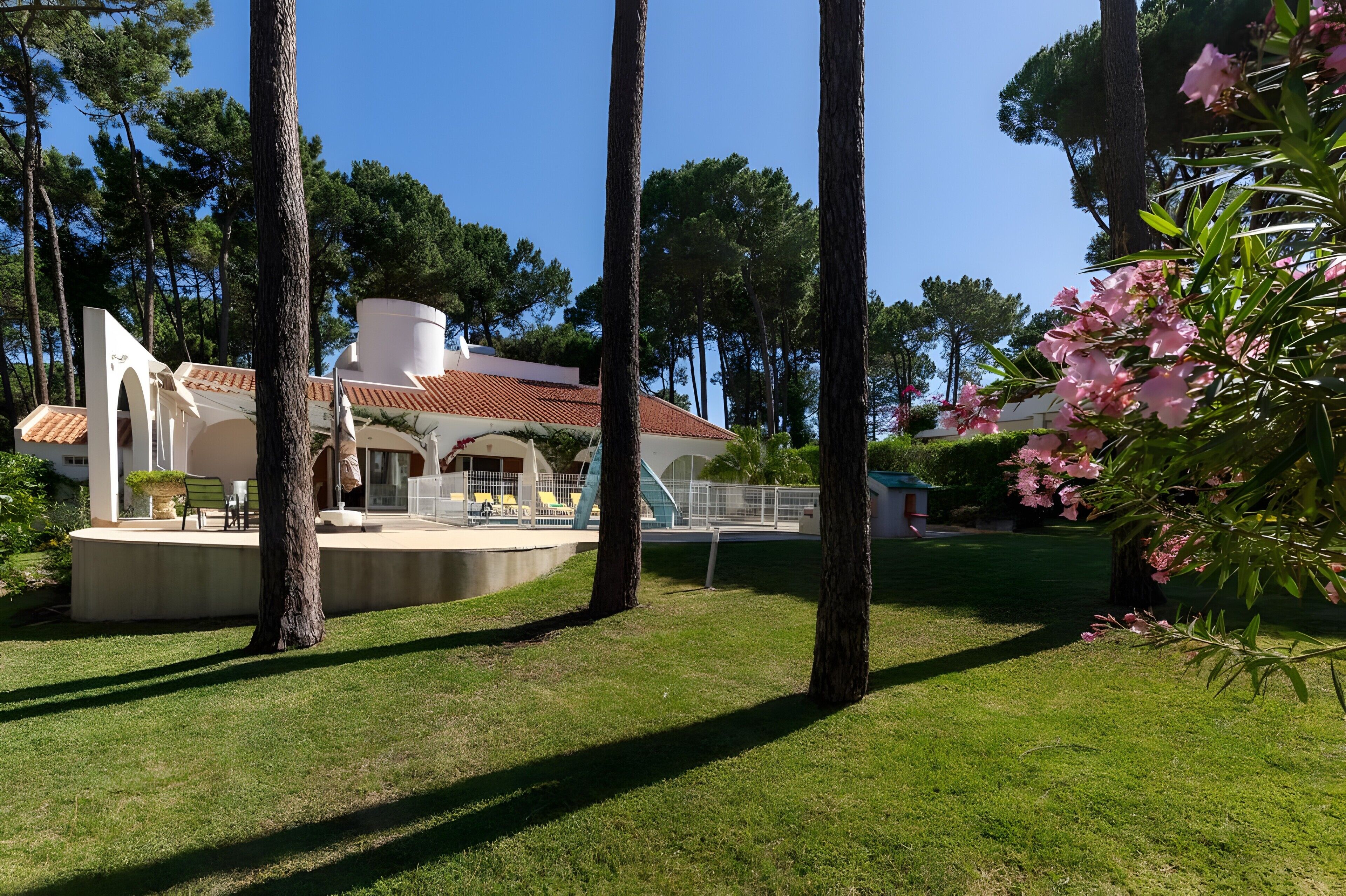 A modern house with a patio, surrounded by trees and a clear sky.
