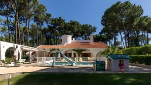 Ein Hotel mit Schwimmbad, Außenbereich zum Sitzen und einer kleinen Kinderspielecke.