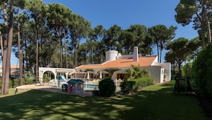 Eine Villa mit Swimmingpool, Gartenmöbeln im Freien und einem Garten.