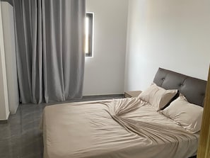 A bedroom with a bed, curtains, and a window.