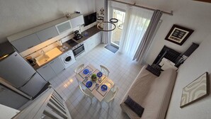 A compact kitchen with a dining area, a sofa, and a staircase. - Lovely semi-detached villa in residence with pool near Richelieu beach, Cap d'Agde (LE CAP D AGDE)