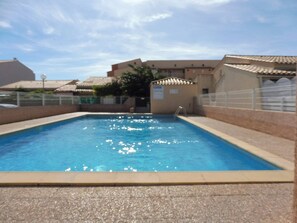 A rectangular swimming pool with clear blue water, surrounded by a pebble-lined deck. - Lovely semi-detached villa in residence with pool near Richelieu beach, Cap d'Agde (LE CAP D AGDE)