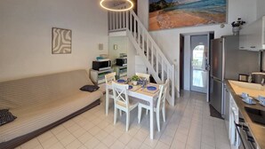 A modern kitchen with a refrigerator, stove, and dining area with a table and chairs. - Lovely semi-detached villa in residence with pool near Richelieu beach, Cap d'Agde (LE CAP D AGDE)