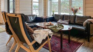 Ett mysigt vardagsrum med en soffa i läder, en trästol, ett soffbord med ett ljus och en mönstrad matta.