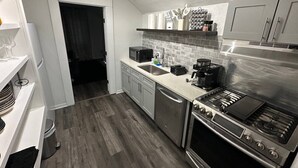 A modern kitchen with stainless steel appliances, a microwave, a coffee maker, and a sink. - 85-in TV|Massage Sofa|3 KING Beds|Walk to UT: ½ mi (Austin)