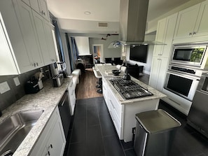 A modern kitchen with granite countertops, stainless steel appliances, and a central island. - 8BR • 2 Kitchens • Walk to UT • Huge TV • Massage (Austin)