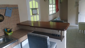 A kitchen with a wooden countertop, a sink, and a window with blinds. - Appart close to everything. (Gros-Morne)