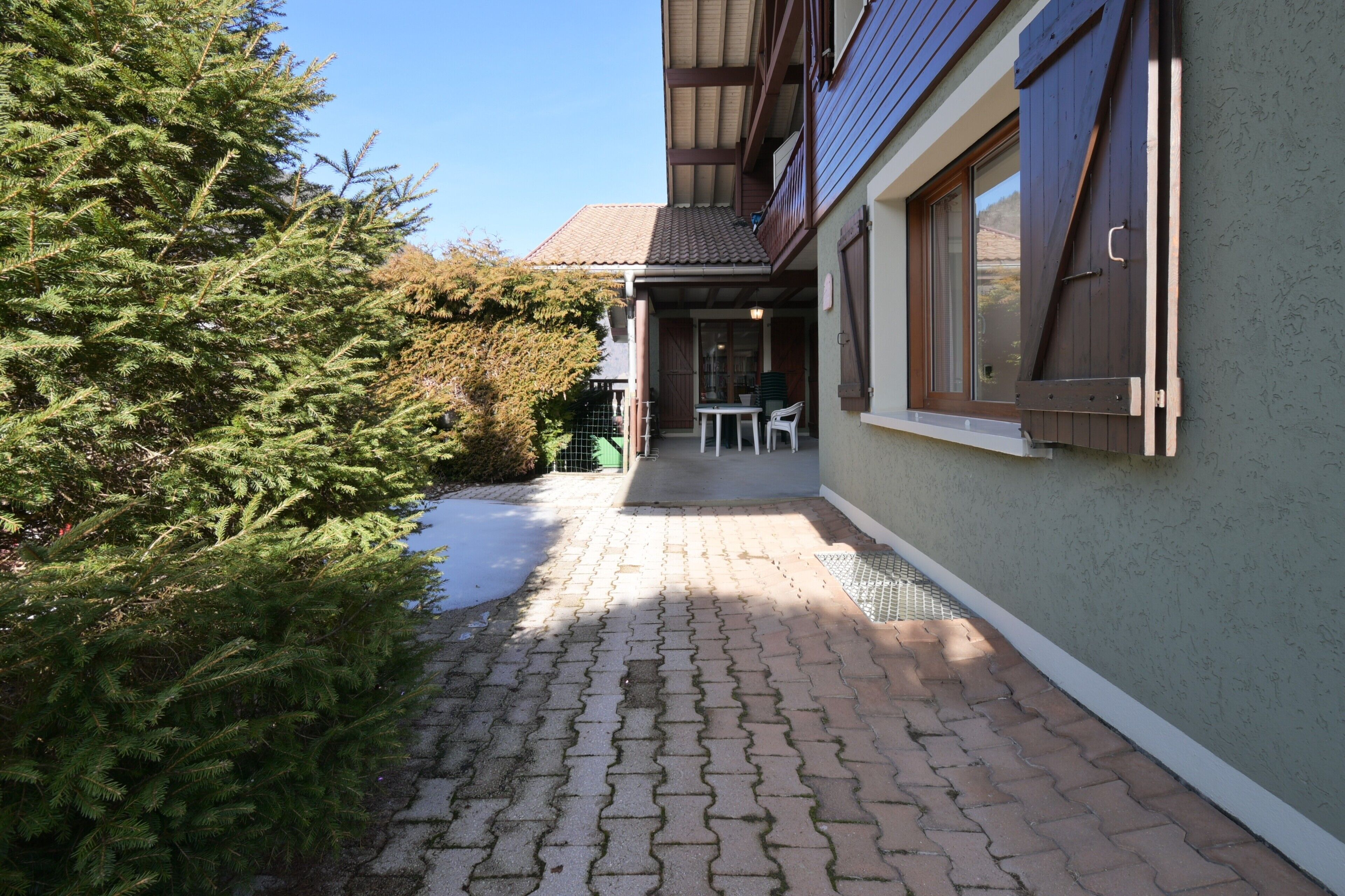 Ein gepflasterter Weg führt zu einem Gebäude mit Balkon, Tisch und Stühlen.
